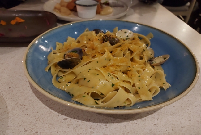 Blue bowl full of linguine like pasta and clams. 